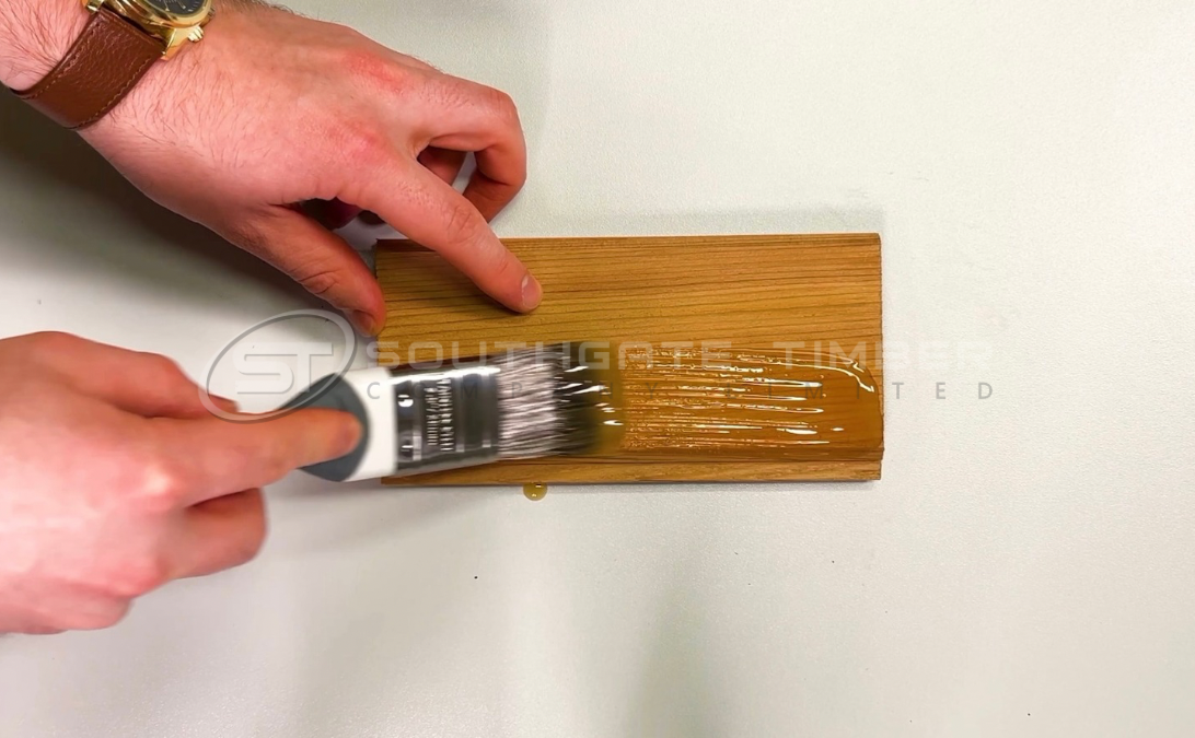 Applying UV-protection oil to a timber cladding board, showing how proper treatment extends lifespan and prevents weathering.